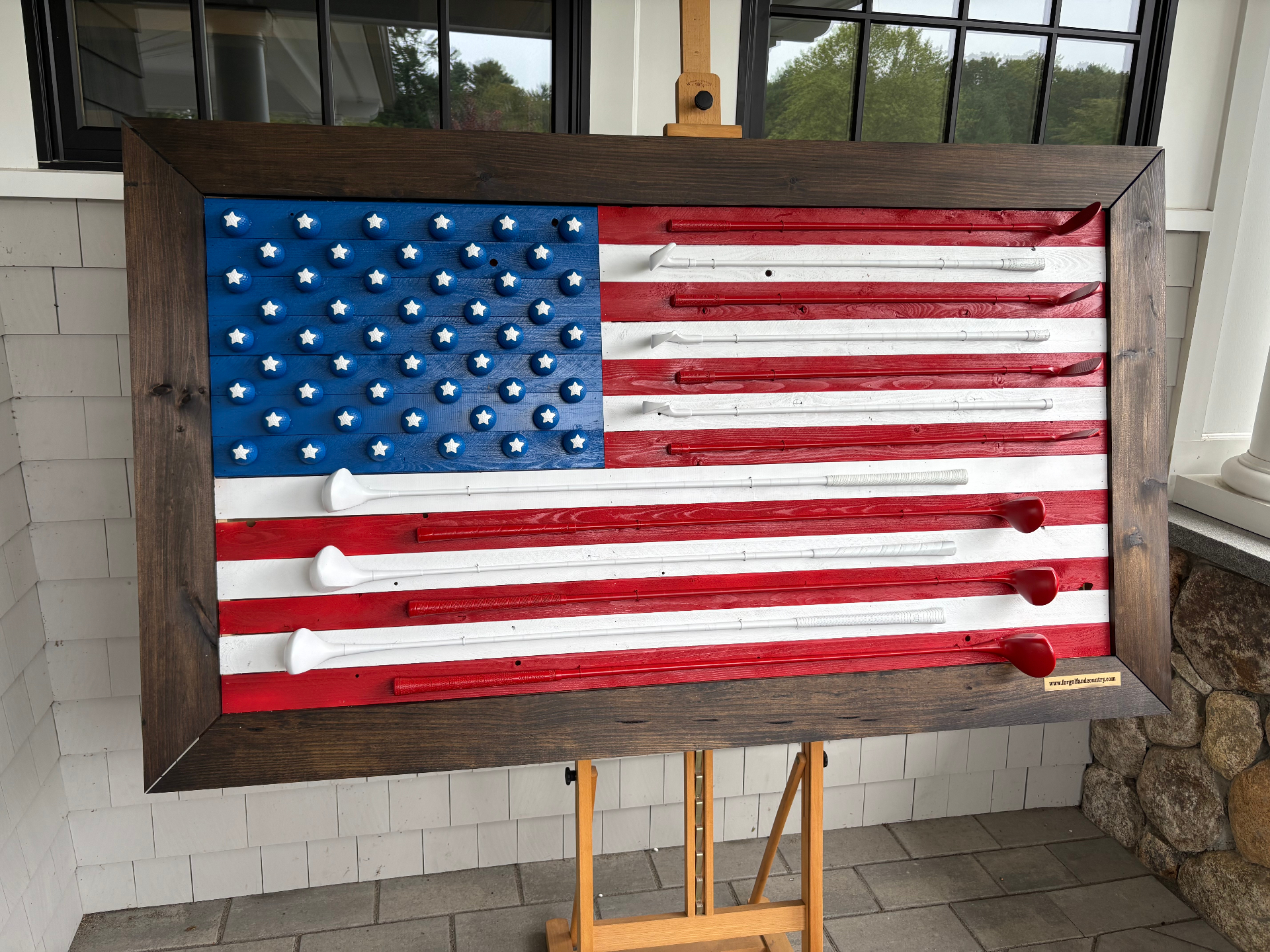 Handcrafted American flag made from real golf clubs and golf balls, displayed on an easel
